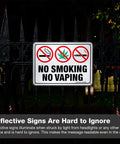 Straight Up Heavy Duty No Smoking And No Vaping Sign 2 Pack Reflective Metal Warning Plaque 10 By 7 Inches mounted on a gate at night.