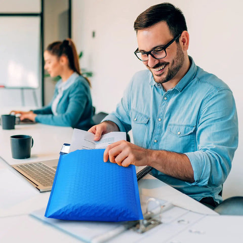 Person placing documents into Blue Large Bubble Mailers 12x16 Inch 25 Pack Usable 12x15 Inch Self Seal Padded Envelopes Waterproof Heavy Duty