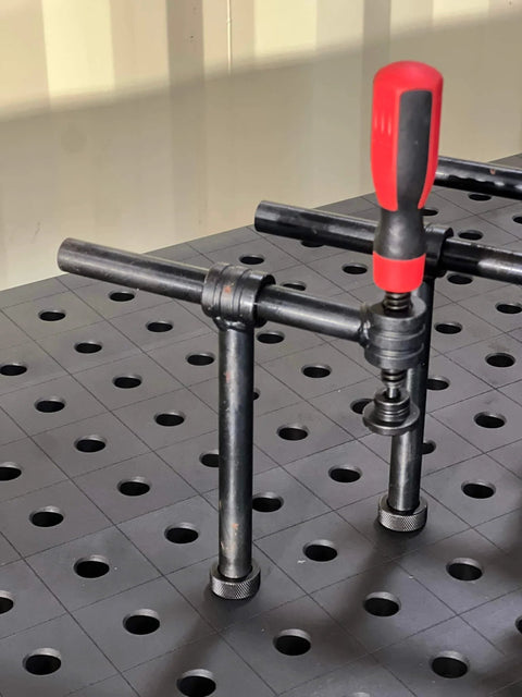 Close-up of 4-Pack 180 Degree Welding Fixture Screw Clamps For Five Eighth Inch Tables installed on a fixture table