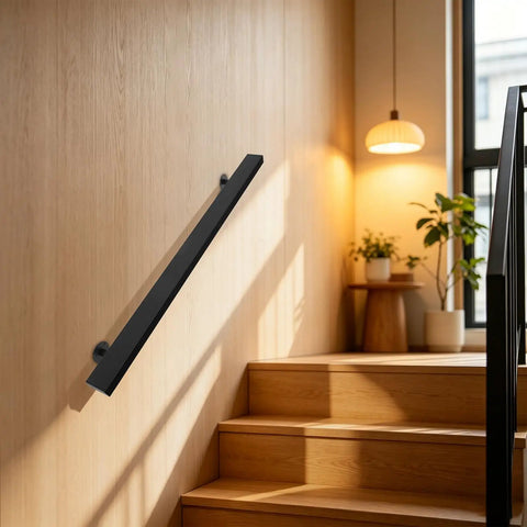 Badass Black Stainless Steel Wall Mount Handrail For Stairs And Hallways With Heavy Duty Support and Tight Secure Grip For Indoor Renovation And Exterior Installations mounted on a wooden wall.