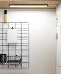 Under Cabinet LED Light Strip 12 Inch Plug In Slim USB Bar 6000K Cool White for Kitchen Cupboard Workbench Shelf Desk Bright Undercounter Lighting No Fuss Easy Install No Tools Needed installed under a wooden cabinet with visible wire and shelf.