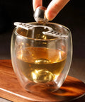 Placing a Coffee Ice Sphere Maker Stainless Steel Ball Mold in a glass for cold brew iced coffee on wooden tray.