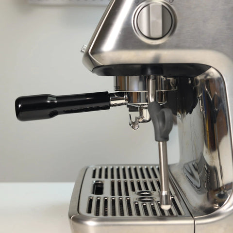 54mm portafilter with black ABS handle installed on a stainless espresso machine; double-spout.