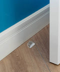 Heavy Duty Acrylic Door Stopper 4 Pack No Drill Sticky Wall Bumpers placed near baseboard on wooden floor.