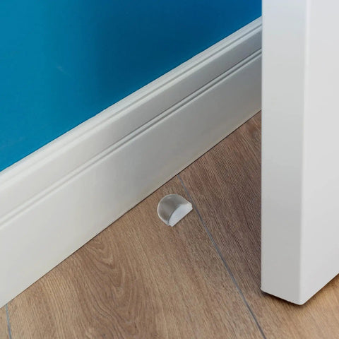 Heavy Duty Acrylic Door Stopper 4 Pack No Drill Sticky Wall Bumpers placed near baseboard on wooden floor.