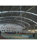 Interior view of a large gymnasium with a high arched ceiling and equipment for sports training.