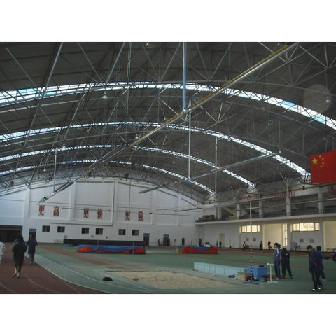 Interior view of a large gymnasium with a high arched ceiling and equipment for sports training.