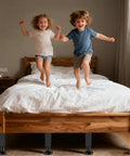 Adjustable Metal Bed Risers 6 Piece Set 10.2 To 16.5 Inches Tall under a wooden bed while kids jump on the mattress.