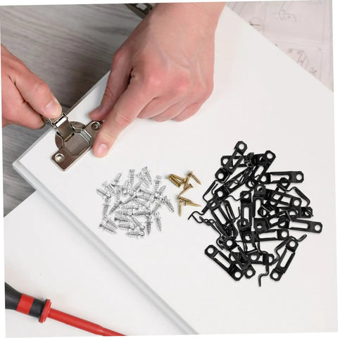 Hands attaching a metal hinge on a wood panel, surrounded by screws and black furniture connector slide buckles.