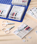 No Fuss Bulk Travel Sewing Crate featuring nifty mini repair packs with needles, threads, scissors, and buttons on a table.