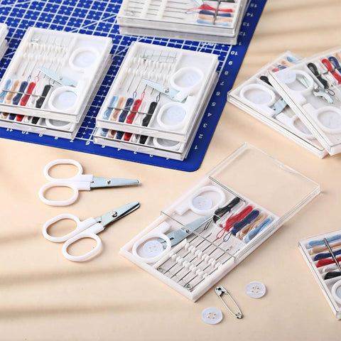 No Fuss Bulk Travel Sewing Crate featuring nifty mini repair packs with needles, threads, scissors, and buttons on a table.