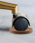 Furniture wheel on a brown plastic caster cup, showing the deep U shape, part of the Brown Couch Stoppers Four Pack Stop Slipping For Sofas Beds Chairs And More Durable Plastic Caster Cups Fit Most Furniture Wheels Under One And A Half Inches With Deep U Shape To Keep Your Furniture In Place.