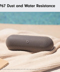 All Day Battery Wireless Bluetooth Speaker With USB C Charging Punchy Bass Up To 24 Hours Of Battery Life IP67 Water Resistant Built In Mic Apple And Android Compatible Dark Gray Portable Party Speaker on towel by pool