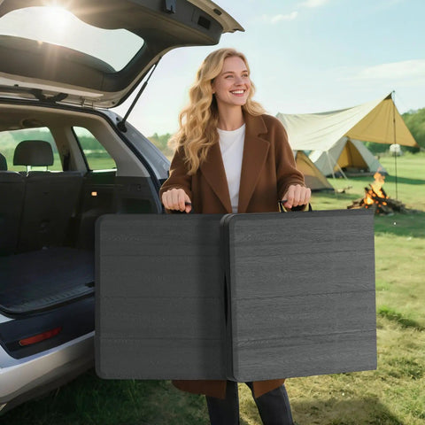 Woman holding folded 4 Foot Folding Table Portable Heavy Duty 400 Lb Capacity With Wood Grain Top beside car at campsite