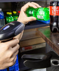 Person using Handheld USB Barcode Scanner, Wired CCD Barcode Reader on bottle, showing easy setup and fast scanning in store setting.