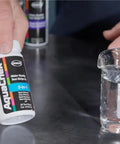 Real Down To Earth Five In One Water Quality Test Strips For Pools And Spas in hand with water sample in beaker.