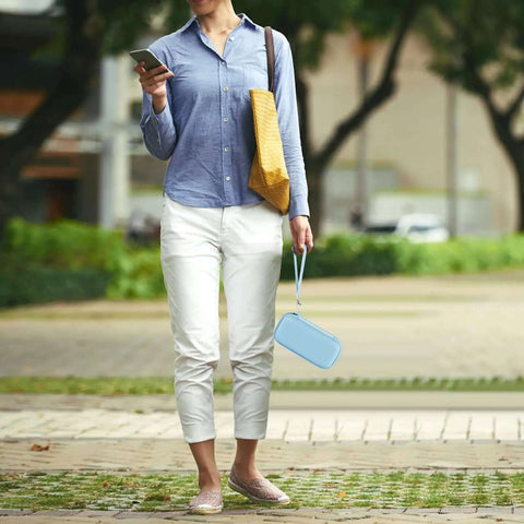 Woman walking with blue Slick Magnetic Battery Sleeve For Portable Chargers in hand, stylish outfit outdoors.