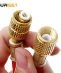 Close-up of two brass refrigerant charging hose fittings with knurled grips and white plastic inserts.