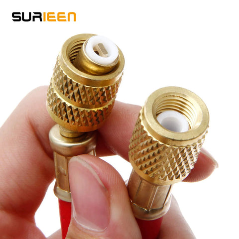 Close-up of two brass refrigerant charging hose fittings with knurled grips and white plastic inserts.