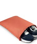 Navy blue sneakers partially inside an orange travel shoe bag