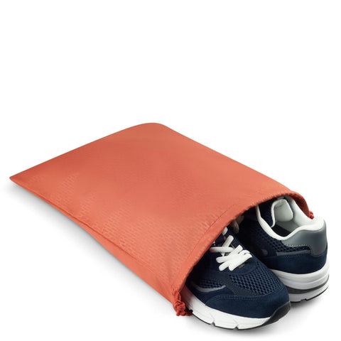 Navy blue sneakers partially inside an orange travel shoe bag