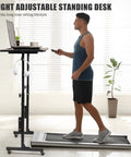 Man using Rollin Standing Desk With Adjustable Height On Wheels For Treadmill Sessions, black, next to walking pad indoors.