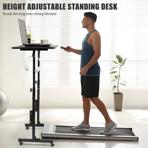 Man using Rollin Standing Desk With Adjustable Height On Wheels For Treadmill Sessions, black, next to walking pad indoors.