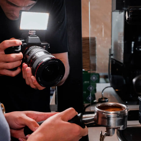 Photographer using Pocket Sized Pro Grade Bicolor Panel Mini LED Light For DSLRs With Adjustable Panel And LCD Display on camera