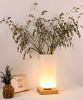Vase Table Lamp With Frosted Glass Shade And Wood Base Dimmable 3 Color LED Bedside Light USB Charge Artistic Vase Lamp glows softly on a tabletop.