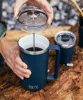 Person using Rambler 34 Oz French Press Coffee Maker With Grounds Control Filter Navy Double Wall Vacuum Insulation outdoors
