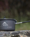 Go To Solo Camping Pot 1.3 Liter with nonstick ceramic coating, lightweight aluminum cook pot, lid and handle on outdoor stone surface.
