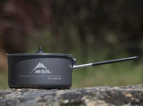 Go To Solo Camping Pot 1.3 Liter with nonstick ceramic coating, lightweight aluminum cook pot, lid and handle on outdoor stone surface.