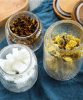Keep Your Stash Fresh With These Top Notch Sealed Tea Canisters And Coffee Bean Jars Crafted From Durable Glass Super Simple Kitchen Pantry Storage Essentials That Are Actually Worth The Buy Hella Convenient: Three glass jars containing sugar cubes and dried tea herbs.