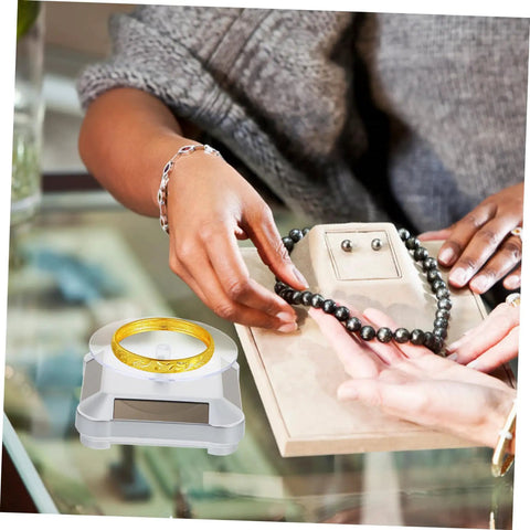 Galpada Solar Powered Jewelry Display Stand With Electric Rotating Turntable For Bracelets And Watches Plus Earrings Store Office Counter Shelf Rack Natural Light Battery Backup Smooth Spin Showcase, showcasing a gold bracelet and a beaded necklace.