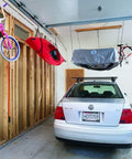 Overhead Garage Hoist System For Lightweight Cargo Carrier To Tuck Kayaks Canoes And Paddle Boards Up High Four Point Hoist 60 LB Max Per Carrier Fits 16 Ft Ceilings Easy One Person Install in use with kayak and cargo overhead in a garage.