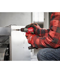 Person using M12 Fuel Half Inch Hammer Drill Driver With Brushless Motor Ultra Lightweight on metal surface for drilling task.