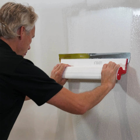 Person using a 32 Inch Composite Skimming Blade For Drywall Finishing With Replaceable 0.3mm German Stainless Steel Insert And Ergonomic Polymer Handle Smooth Mud Like Butter Easy Precision Pro Grade Finish on wall