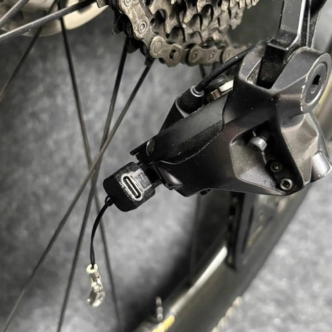 Close-up of Type C Battery With Lanyard For 12 Speed E Bike Replacement Adapter with electronic shifting near bike wheel gear.