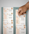 Hand reaching for a Heavy Duty Replacement Time Card CR1000 from a holder, featuring employee shift information and QR codes.