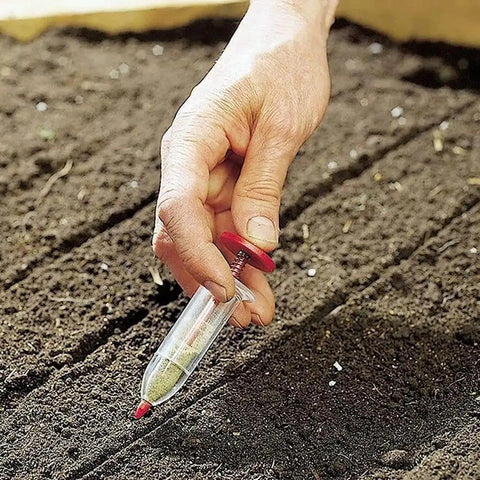 Compact Handheld Seed Spreader For Precise Sowing In Lawns, Gardens And Planters in use on soil bed.