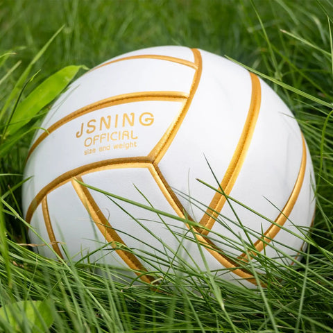 Golden White Volleyball Official Size 5 with minimalist design and vibrant colors resting on green grass, durable poly cover.