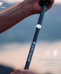 Close-up of hand holding Ultra Lightweight Aluminum Collapsible Trekking Poles With Cork Grips, showing patented lock button.