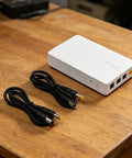 Keep The Wifi Alive With This Solid 7800mAh UPS Battery Backup with DC cables on wooden surface.