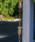 Copper Pineapple Rain Chain Eight And A Half Foot Long Handcrafted 20 Gauge Pure Copper With Brass Accents hanging outdoors