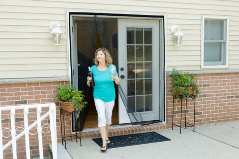 Woman walking through Magnetic Screen Door For French And Sliding Doors, Heavy-Duty Hands-Free Fiberglass Mesh With Self-Closing Magnetic Seal, Black Trim, Fits 70x80 Inch Doors, Screen Size 72x82 installed in a home.