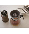 Premium Japanese Ceramic Coffee Filter Reusable Pour Over Dripper With Rock Solid Brown Holder in use with coffee grinder.