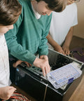 Three individuals working on a computer with a 500 Piece Laptop Screw Kit With Flat Head Self Tapping Screws For Laptop Motherboard And Graphics Card Carbon Steel Quick Install And Easy Storage Case Get It Done Fast PC Repair And Maintenance visible on the table.