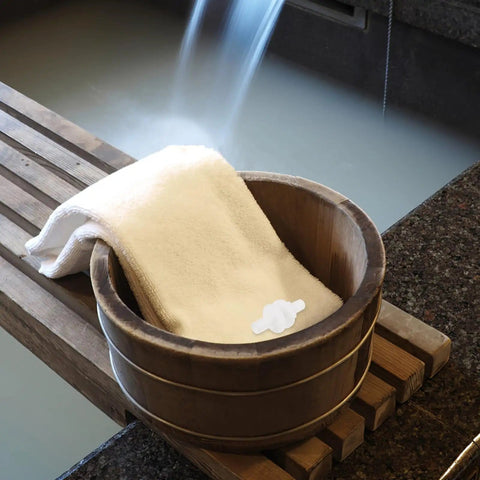 Wooden sauna bucket with towel, beside steaming water, showing serene spa setting. Sauna Steamer Connector Hose Joint Durable Plastic Replacement Fitting For High Temperature Steam Pots Easy Snap In Upgrade For Home Sauna Setup No Fuss Long Lasting Steam Pot Accessory Perfect For Sauna Enthusiasts Or DIY Spa Renovations