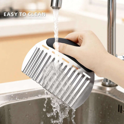 Stainless steel potato crinkle cutter with black handle; hand-held side view under running water.