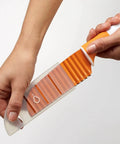 Stainless steel crinkle-cut knife with orange handle and clear sheath for vegetables.